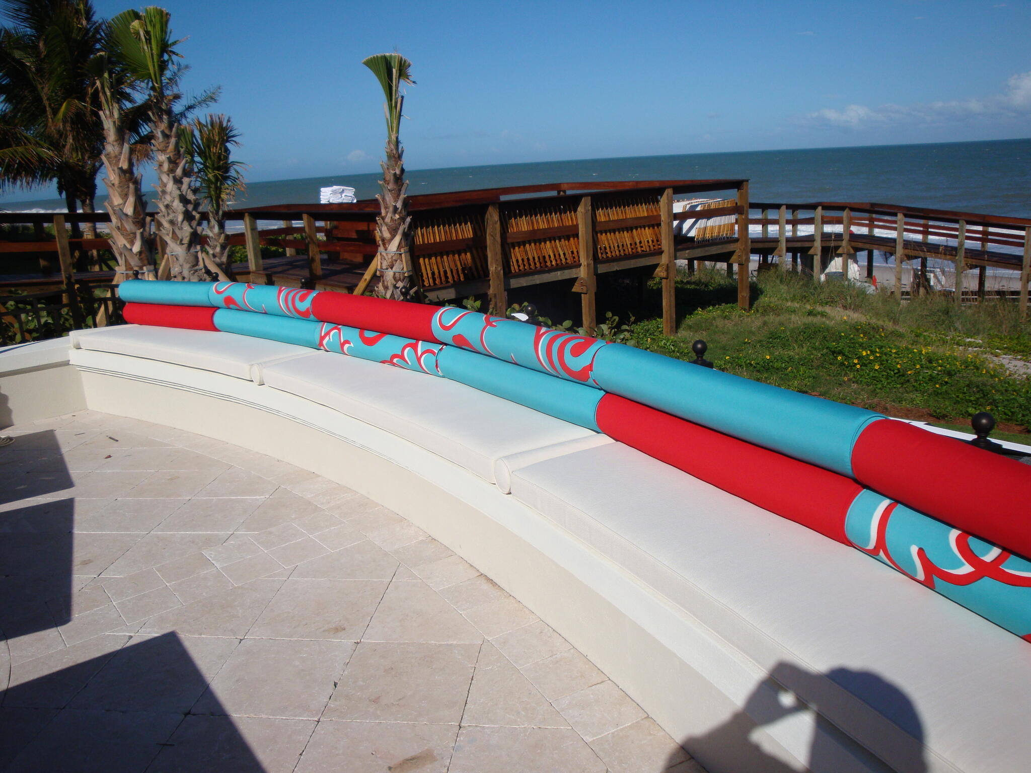Turquoise and red upholstered seating beside the ocean